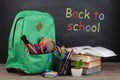 Education concept - school backpack with books and other supplies, blackboard background Royalty Free Stock Photo