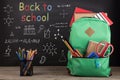 Education concept - school backpack with books and other supplies, blackboard background Royalty Free Stock Photo