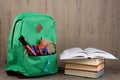 Education concept - school backpack with books and other supplies on the desk