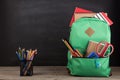 Education concept - school backpack with books and other supplies, blackboard background Royalty Free Stock Photo