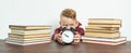The schoolboy sits at the table and holds an alarm clock in his hands. Sharpness of the image on the alarm clock Royalty Free Stock Photo