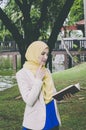 Smile face young muslimah woman standing and holding notebooks in park.