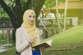 Muslimah woman standing and holding notebooks