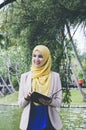 Smile face young muslimah woman standing and holding notebooks in park.