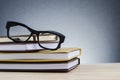 Spectacles on stack of books over beautiful gradient background with reverberation