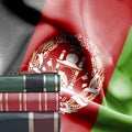 Education concept - Stack of books and reading glasses against National flag of Afghanistan