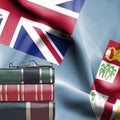 Education concept - Stack of books and reading glasses against National flag of Fiji