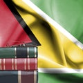 Education concept - Stack of books and reading glasses against National flag of Guyana Royalty Free Stock Photo