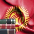 Education concept - Stack of books and reading glasses against National flag of Kyrgyzstan