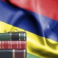 Education concept - Stack of books and reading glasses against National flag of Mauritius