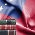 Education concept - Stack of books and reading glasses against National flag of Samoa
