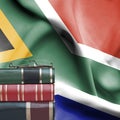 Education concept - Stack of books and reading glasses against National flag of South Africa