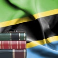 Education concept - Stack of books and reading glasses against National flag of Tanzania