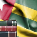 Education concept - Stack of books and reading glasses against National flag of Togo