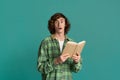 Education concept. Stunned teenager with open book on color background