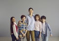 Happy smiling schoolteacher posing with her pupils over studio grey background