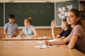 Education, elementary school. Learning and people concept - group of school kids with pens and notebooks writing test in Royalty Free Stock Photo