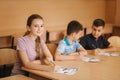 Education, elementary school. Learning and people concept - group of school kids with pens and notebooks writing test in Royalty Free Stock Photo