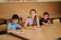Education, elementary school. Learning and people concept - group of school kids with pens and notebooks writing test in Royalty Free Stock Photo