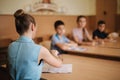 Education, elementary school. Learning and people concept - group of school kids with pens and notebooks writing test in Royalty Free Stock Photo