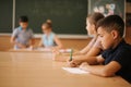 Education, elementary school. Learning and people concept - group of school kids with pens and notebooks writing test in