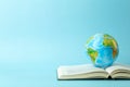 Education and globalism concept. Globe on an open book on a table in a university class on a blue background