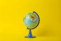 Education and globalism concept. Globe on an open book on a table in a university class on a yellow background