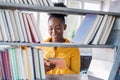 Education, high school and knowledge concept - African student woman with books over shelves in librarry. African american girl Royalty Free Stock Photo