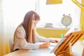 Education at home concept - Cute little girl with long hair studying or completing home work on a table with pile of books and