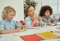 Education is key. Lovely diverse kids studying and making notes while sitting together at the table in elementary school