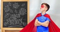 boy in super hero costume over school blackboard