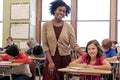 Education, learning and portrait of teacher with girl writing exam or test at Montessori school with students. Black Royalty Free Stock Photo