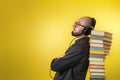 Education and modern technologies. The concept of audio books. A man in glasses, shirt, and earphones leaned against stack of