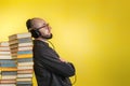 Education and modern technologies. The concept of audio books. A man in glasses, shirt, and earphones leaned against stacks of