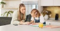 Education, mother and girl writing in kitchen for school task, assignment or homework. Help, learning and mom with child Royalty Free Stock Photo