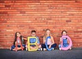 Education opens the mind. Portrait of a group of young children holding letters from the alphabet against a brick wall.