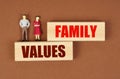 On wooden blocks with the inscription - family values, there are miniature figures of people.