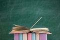 Education and reading concept - group of colorful books on the wooden table in the classroom, blackboard background Royalty Free Stock Photo