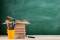 Education and reading concept - group of colorful books on the wooden table in the classroom, blackboard background Royalty Free Stock Photo