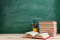 Education and reading concept - group of colorful books on the wooden table in the classroom, blackboard background Royalty Free Stock Photo