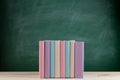 Education and reading concept - group of colorful books on the wooden table in the classroom, blackboard background Royalty Free Stock Photo