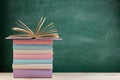 Education and reading concept - group of colorful books on the wooden table in the classroom, blackboard background Royalty Free Stock Photo