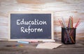 Education Reform text on a blackboard. Old wooden table with texture