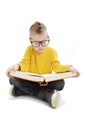 Education and school concept - adorable boy with eyeglasses sitting on floor and reading book Royalty Free Stock Photo