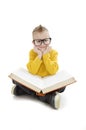 Education and school concept - adorable boy with eyeglasses sitting on floor and reading book. Royalty Free Stock Photo
