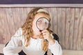 education and school concept - little girl with magnifier at school. schoolgirl sitting in the classroom. Child in an Royalty Free Stock Photo