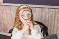 education and school concept - little girl with magnifier at school. schoolgirl sitting in the classroom. Child in an Royalty Free Stock Photo