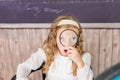 education and school concept - little girl with magnifier at school. schoolgirl sitting in the classroom. Child in an Royalty Free Stock Photo