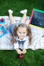 Education and school concept. Preschool education. Happy little preschool child girl with a red apple is resting in the park for l Royalty Free Stock Photo