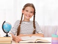 Education and school concept. Smiling child is sitting at the desk and reading a book Royalty Free Stock Photo